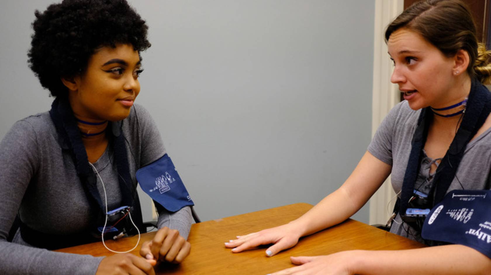 Two young people in blood pressure cuffs talking