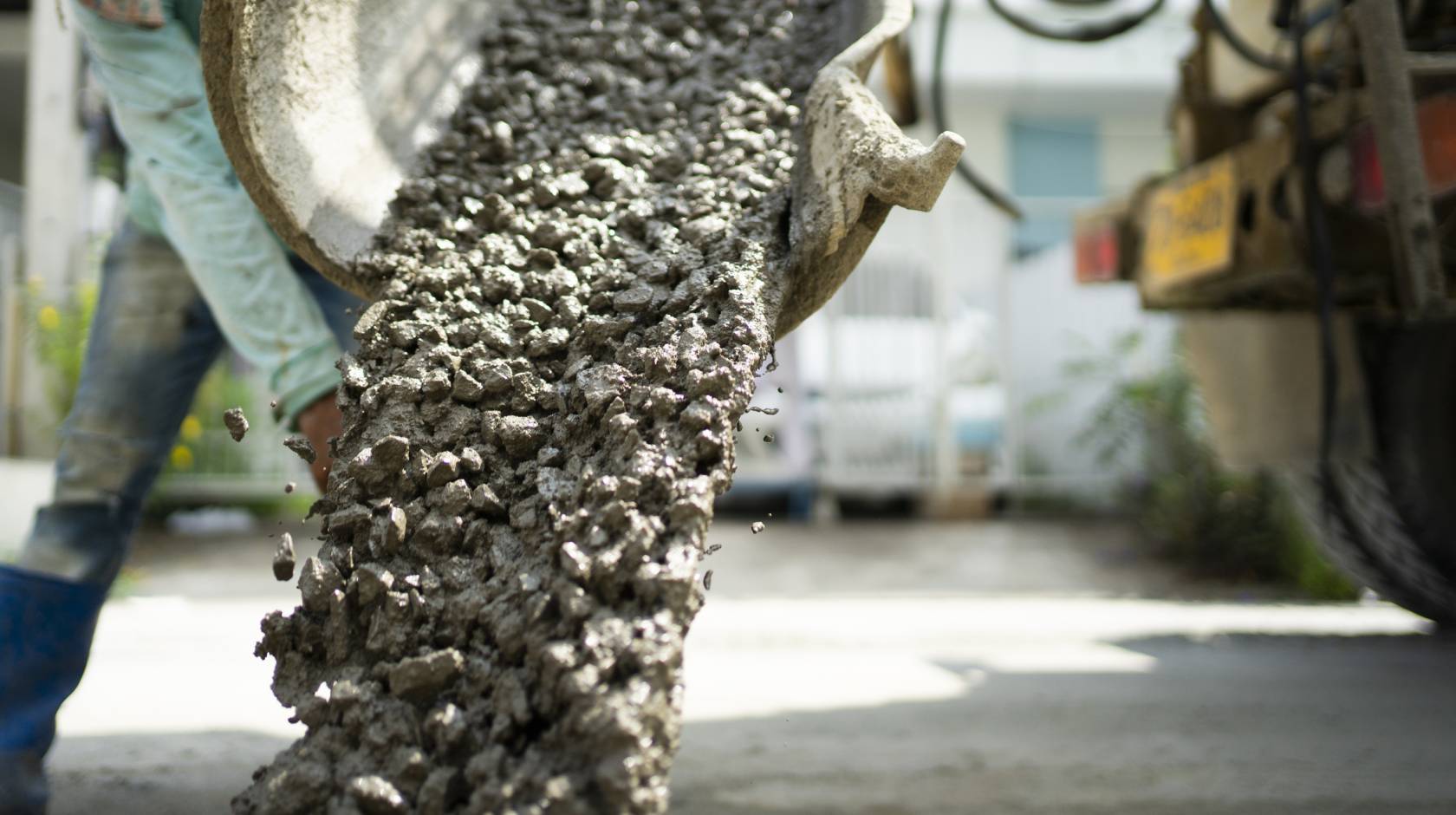 Cement being poured with a worker blurry in the background