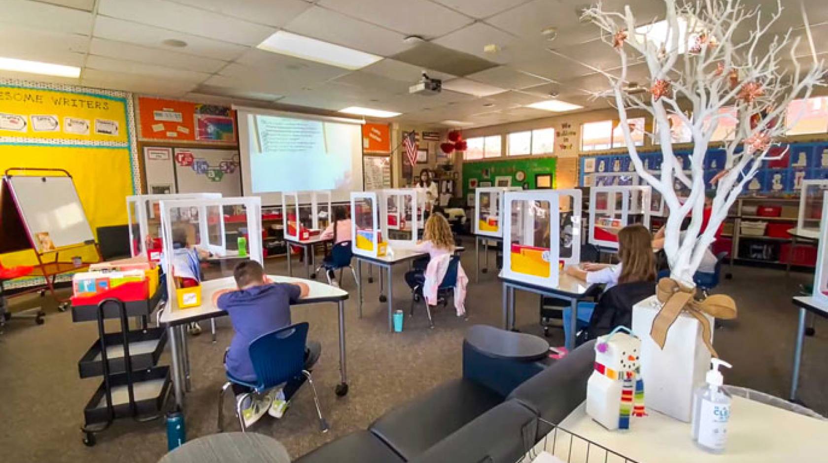 Kids at a school with COVID-19 plastic guards around desks