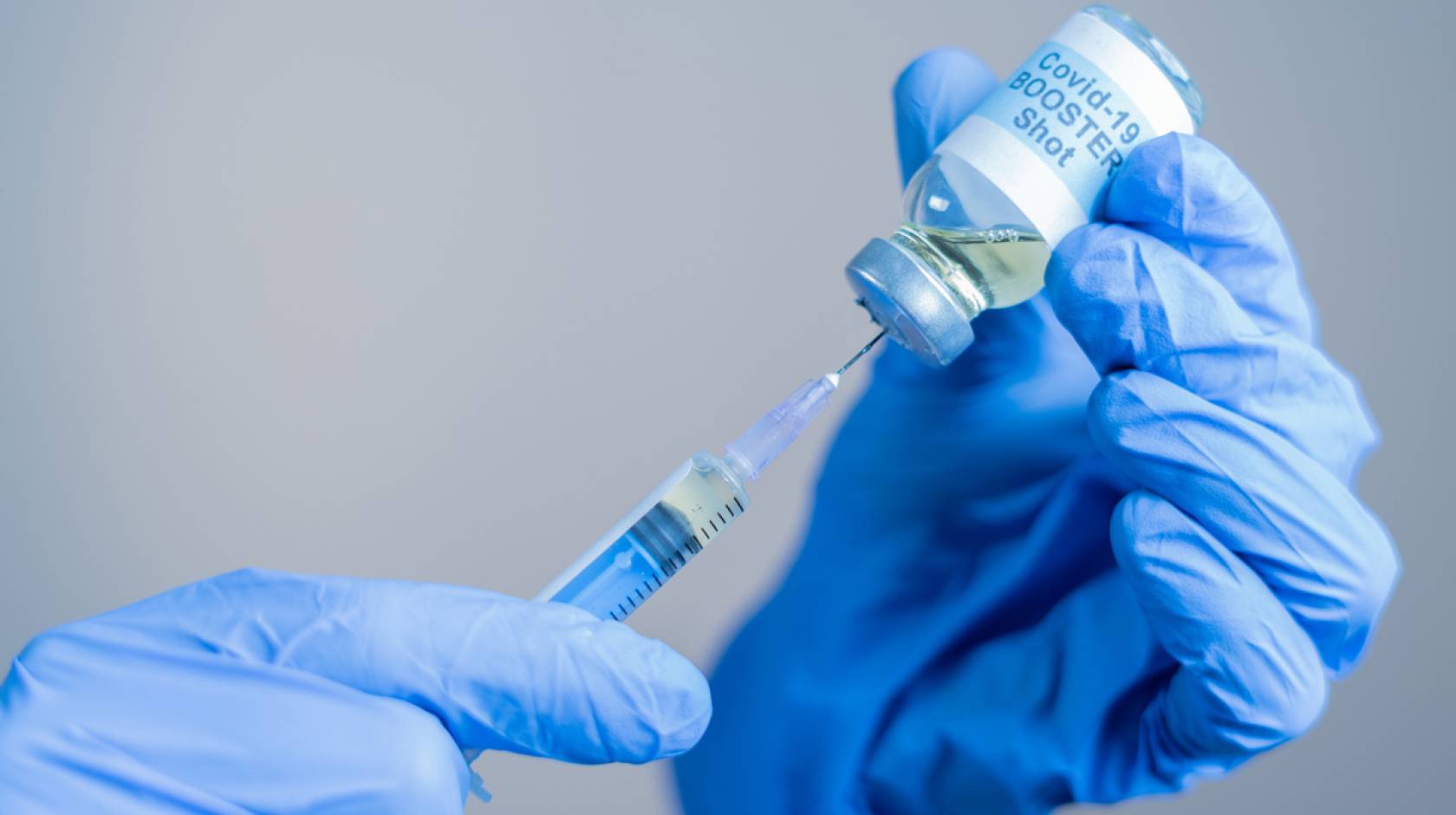 Close up of doctor or nurse's hands preparing to administer a COVID-19 booster shot