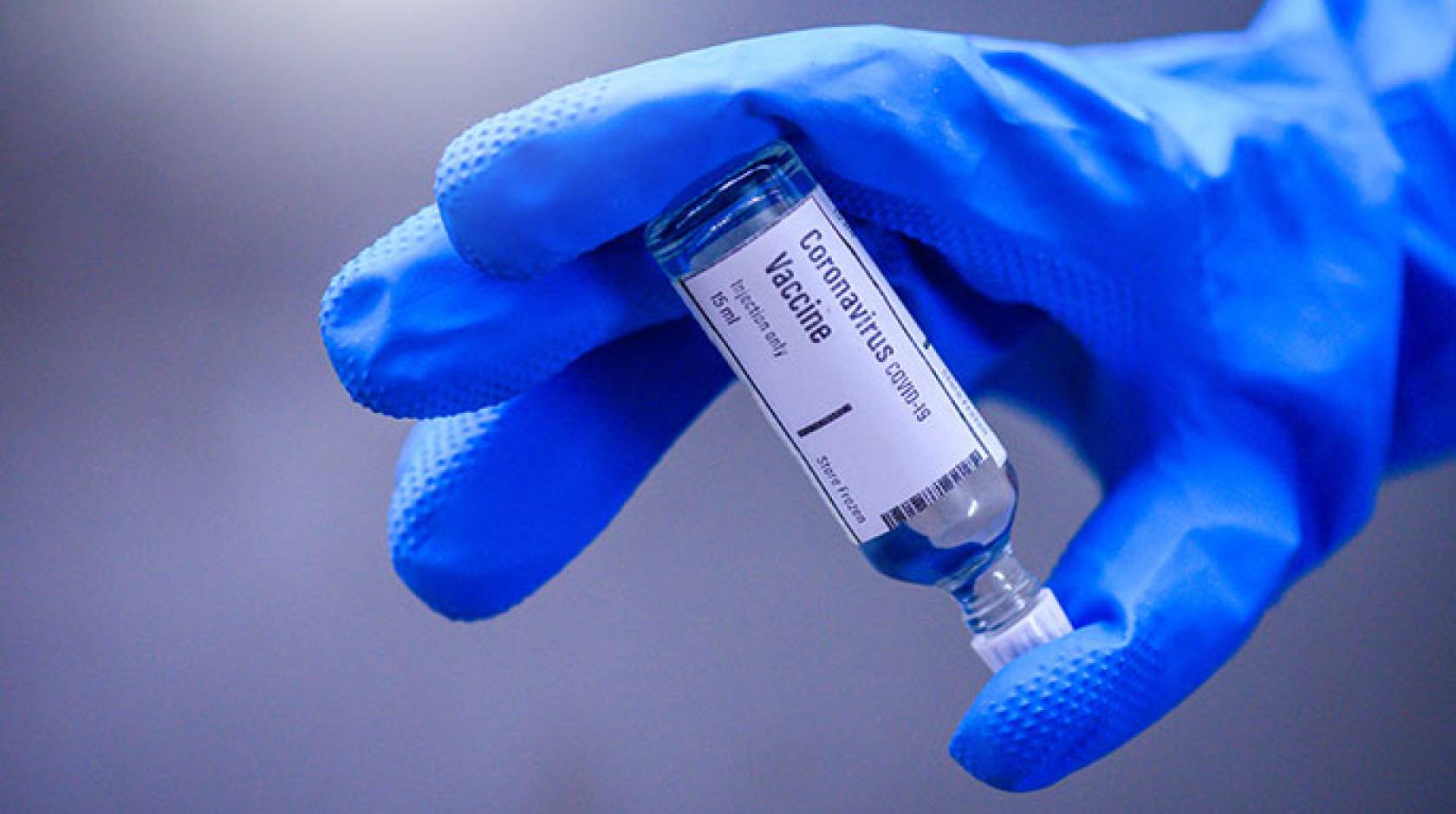 Blue glove holding a COVID-19 vaccine