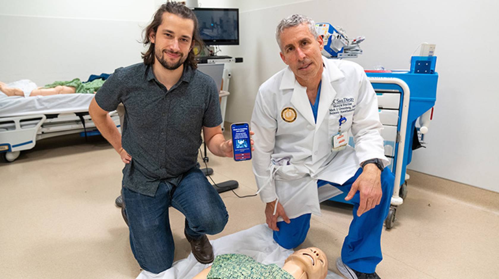 Medical student and a doctor kneeling over a CPR dummy with the app