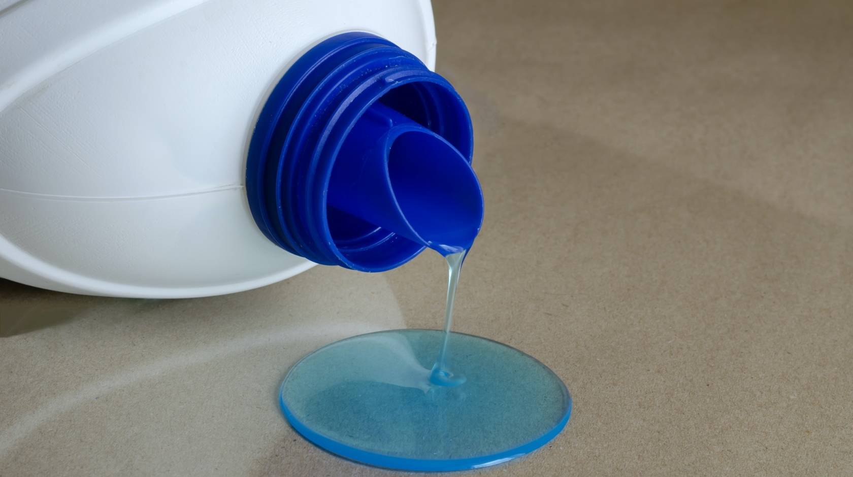blue liquid spilling out of a plastic laundry detergent bottle
