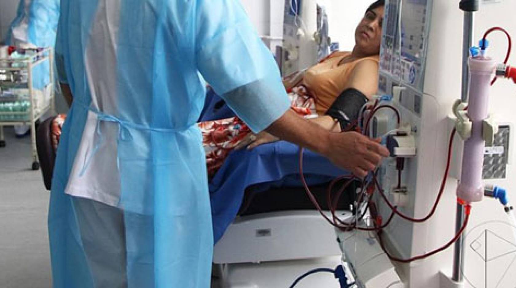 Nurse operating dialysis machine next to a woman