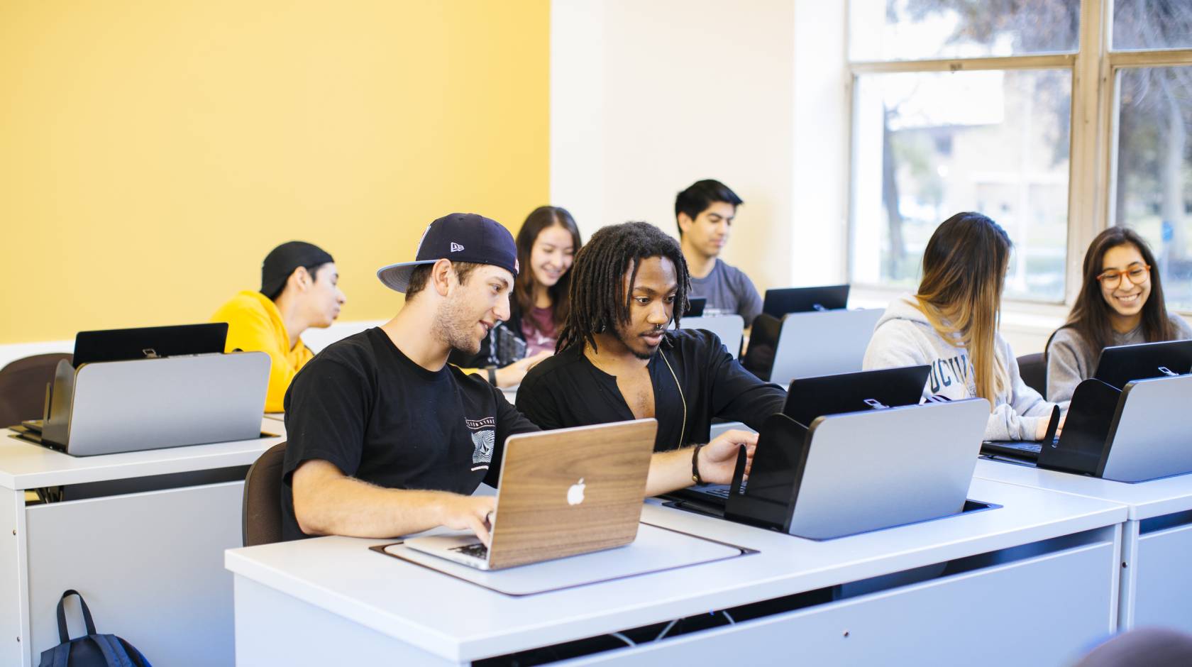 Diverse students looking at computers together in a classroom