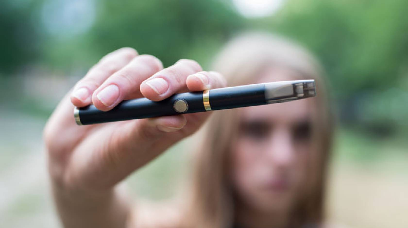 E-cigarette held up by a blurred out teenager