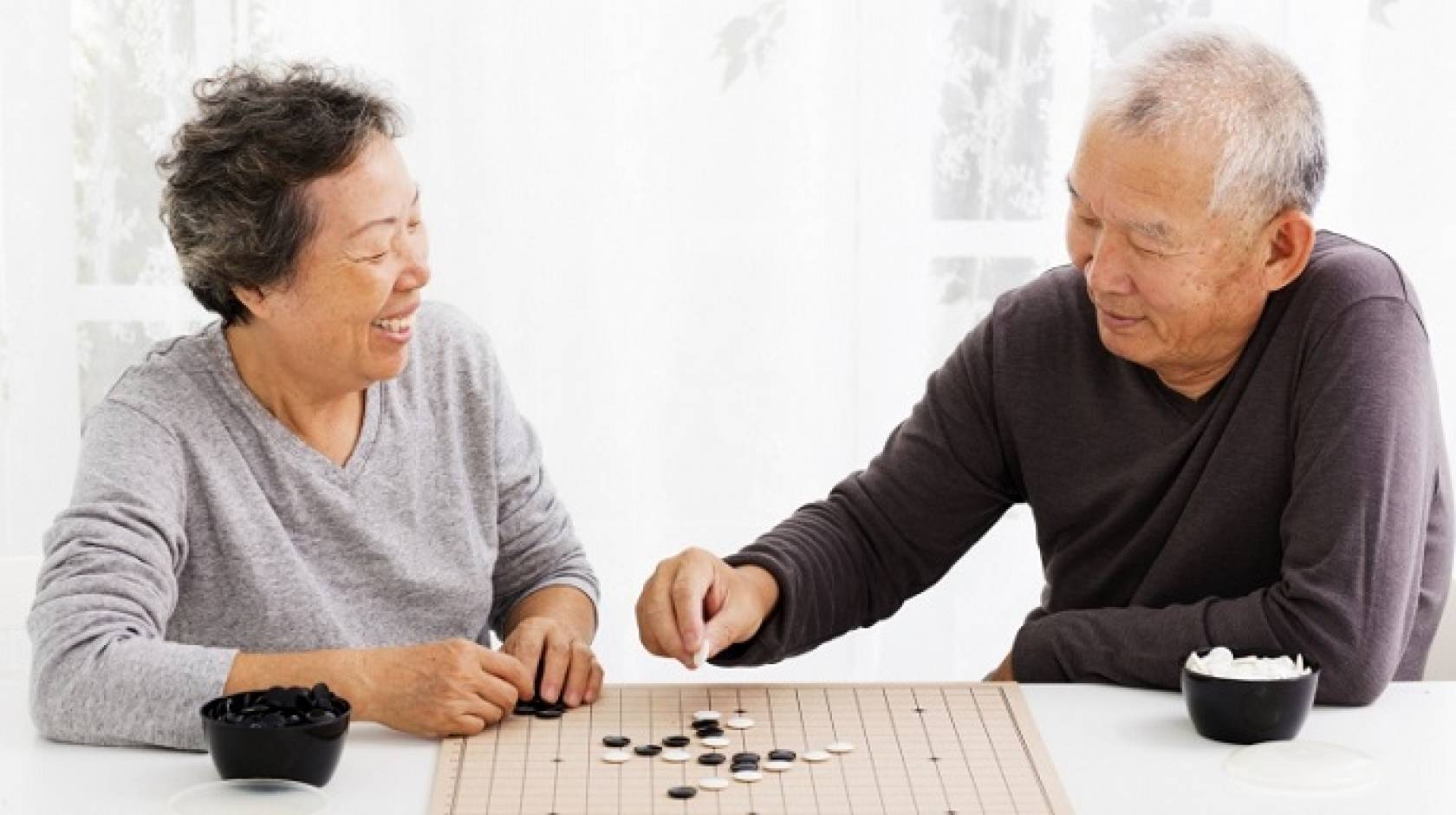 An elderly Asian couple plays a game