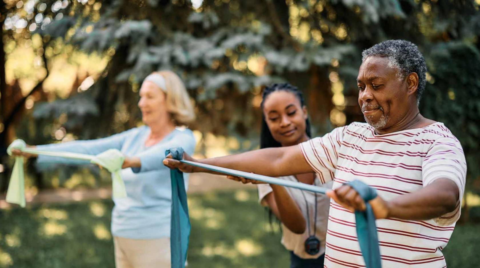 Exercise coach with seniors doing arm exercises with therapy bands