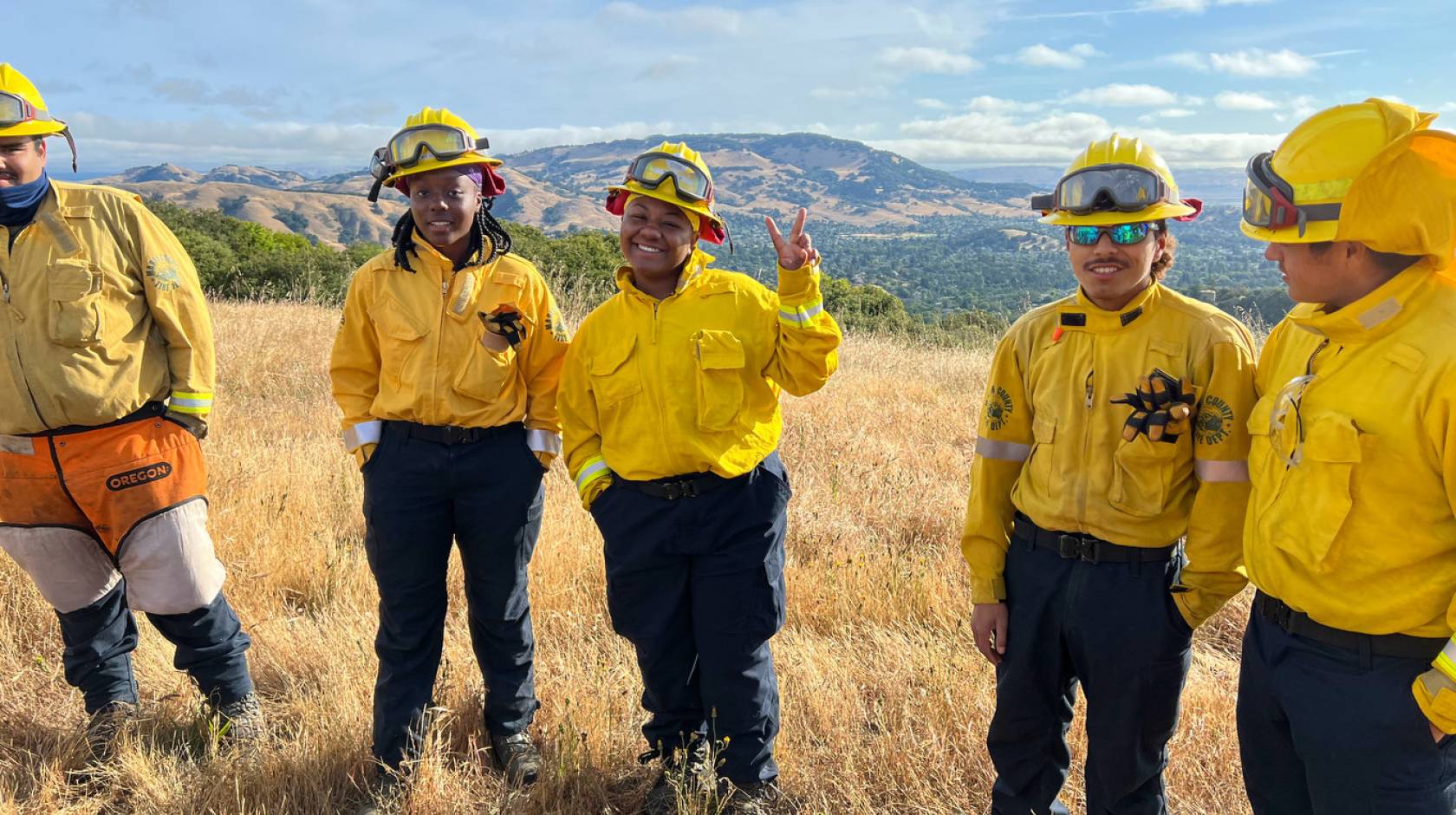 Young African American and Latino firefighters smile at camera
