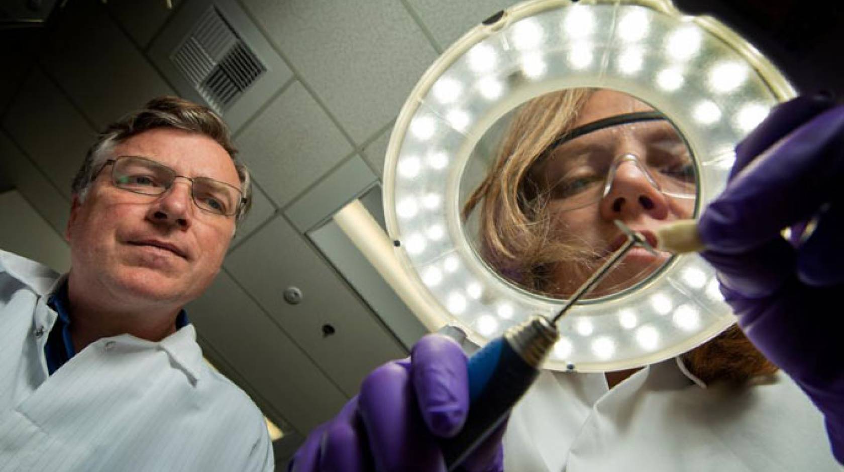 Two scientists in lab coats looking at a tooth sample