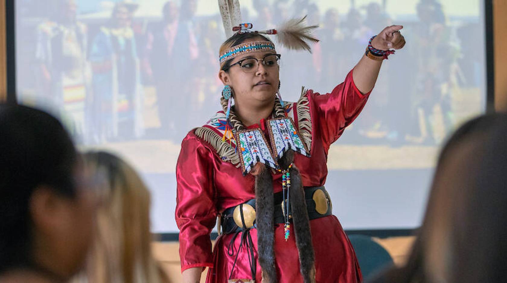 Young woman in tribal dress at the front of a classroom