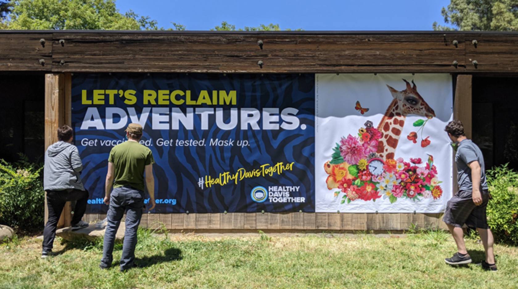 Artists in front of a banner promoting vaccination with a giraffe on it