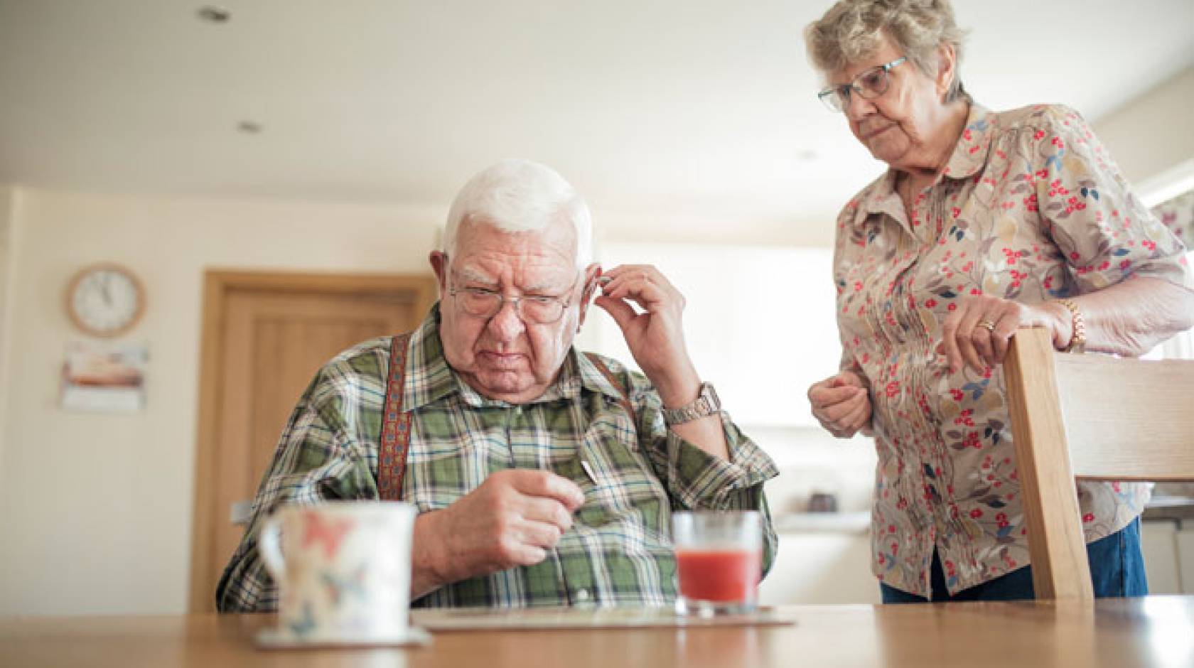 Hearing aid adjusted by senior man with senior woman nearby