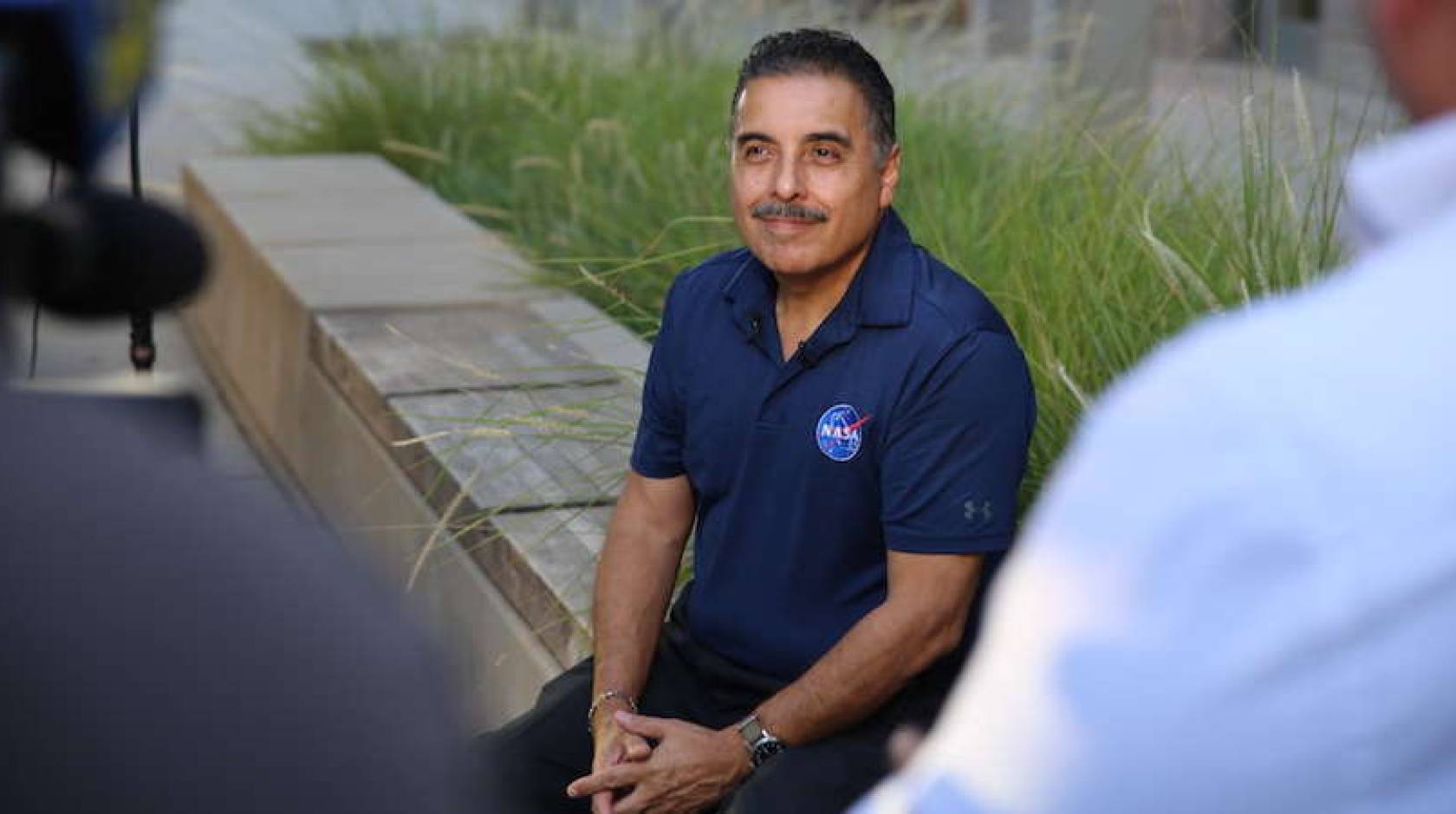 José Hernández sitting outside in a NASA polo