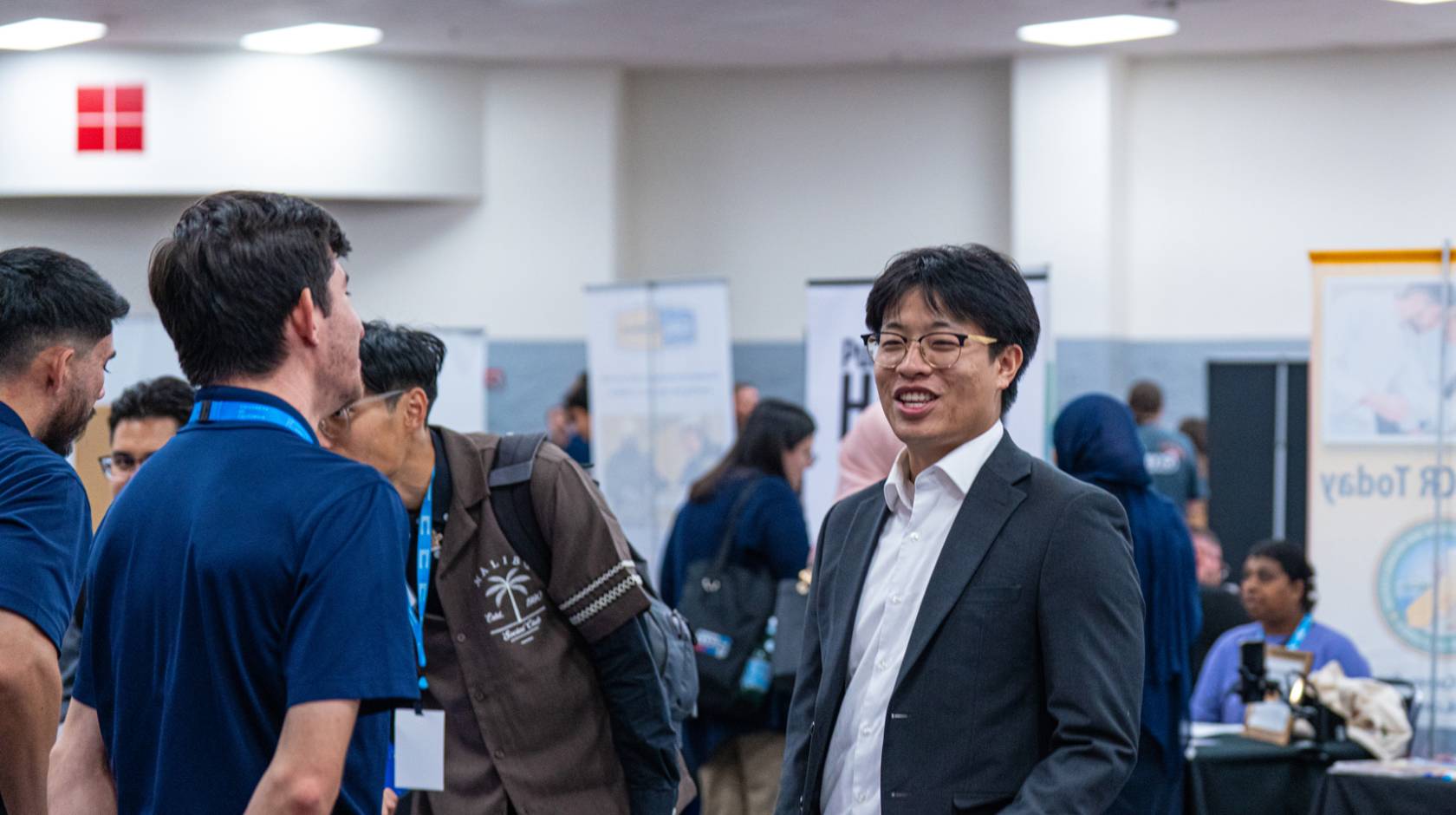 A number of people at a career fair with booths indoors