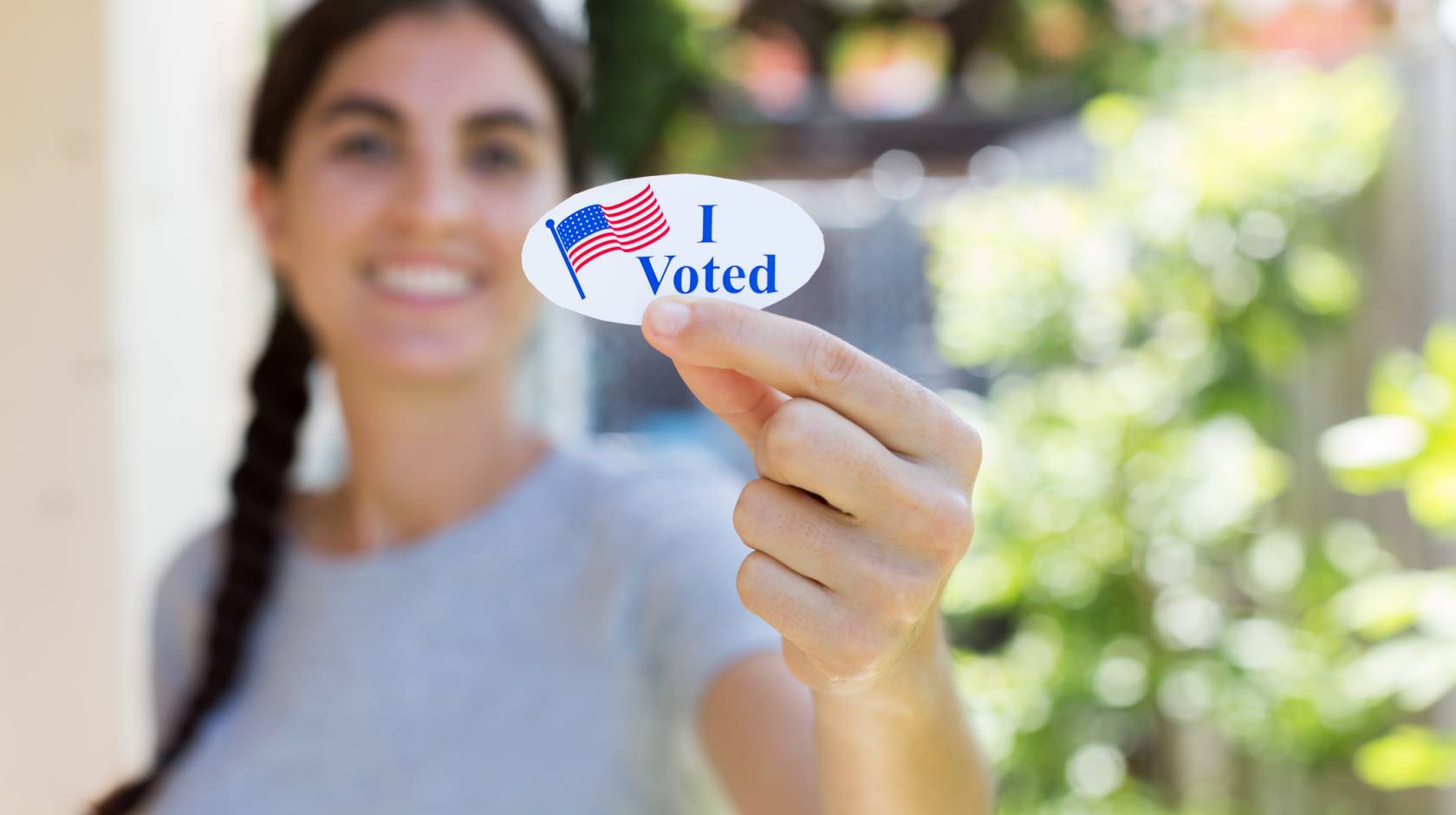 Young woman holding up an I Voted sticker