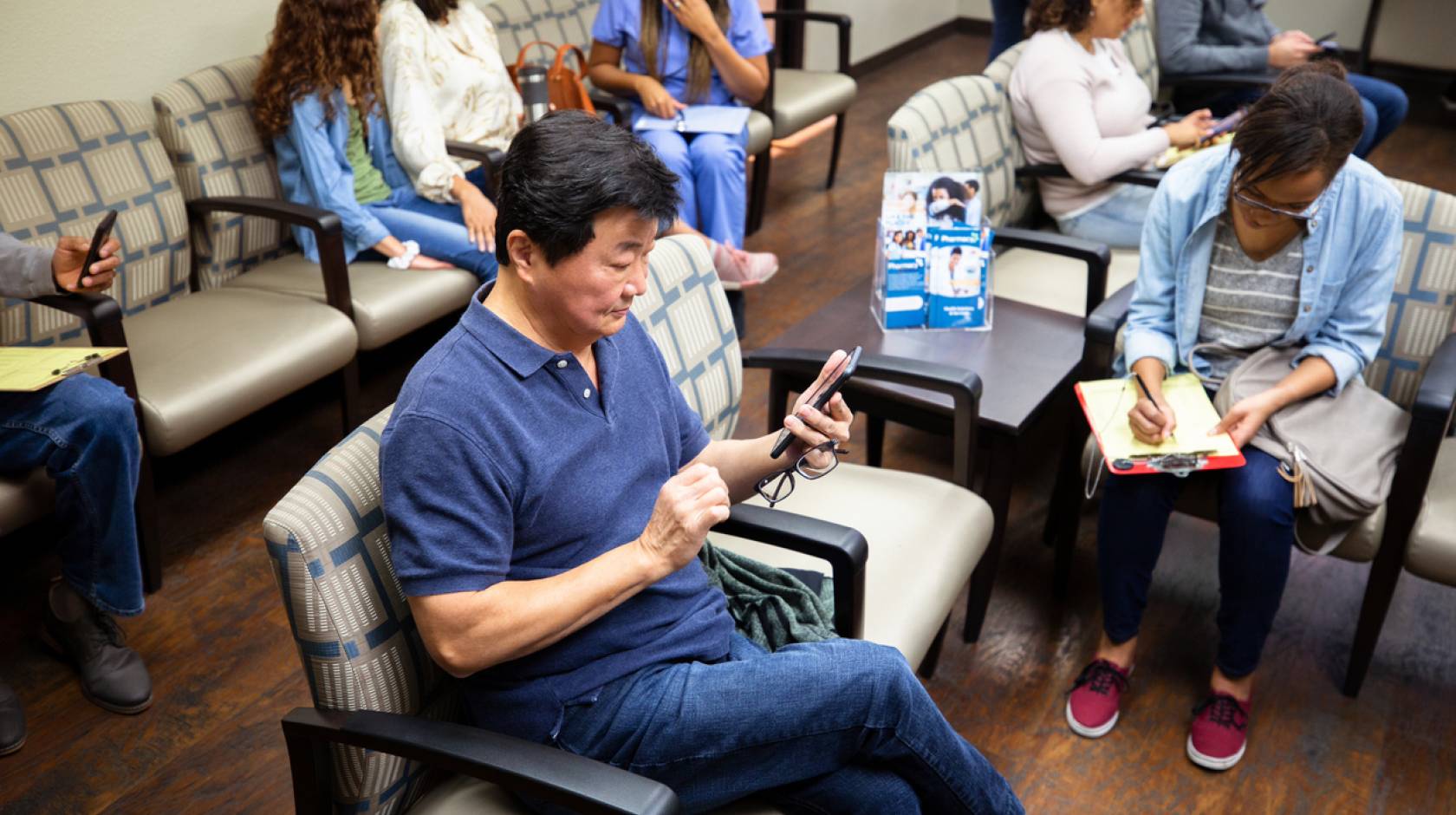 Man looks at his cell phone while waiting at a medical clinic