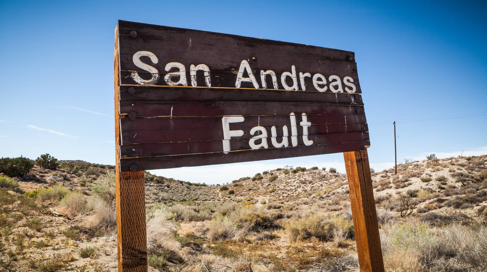 Desert landscape with an old wooden sign reading, San Andreas fault