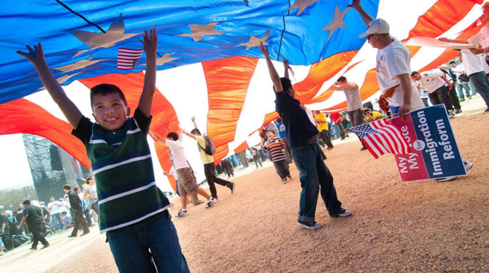 A child and several others under a large American flag