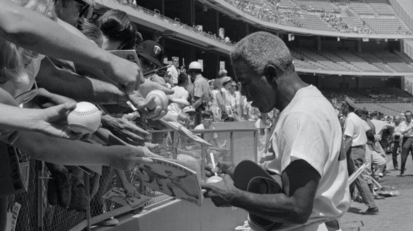 Jackie Robinson signing autographs at a game