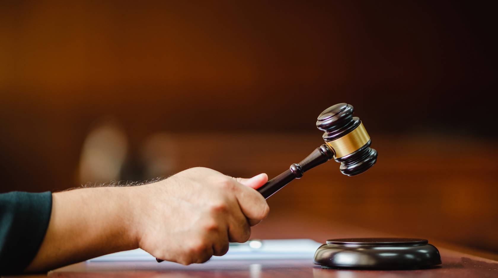 Closeup hand of a woman Judge with gavel at wooden table indoors at the courtroom