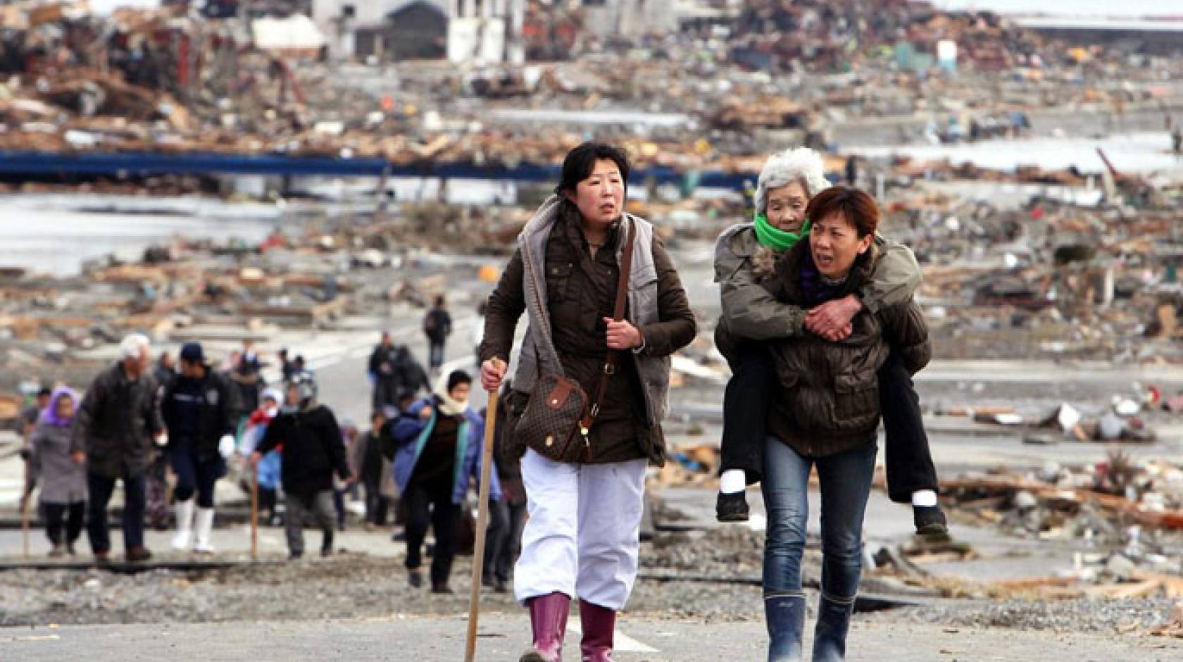 Two women walking, one carrying another, older woman