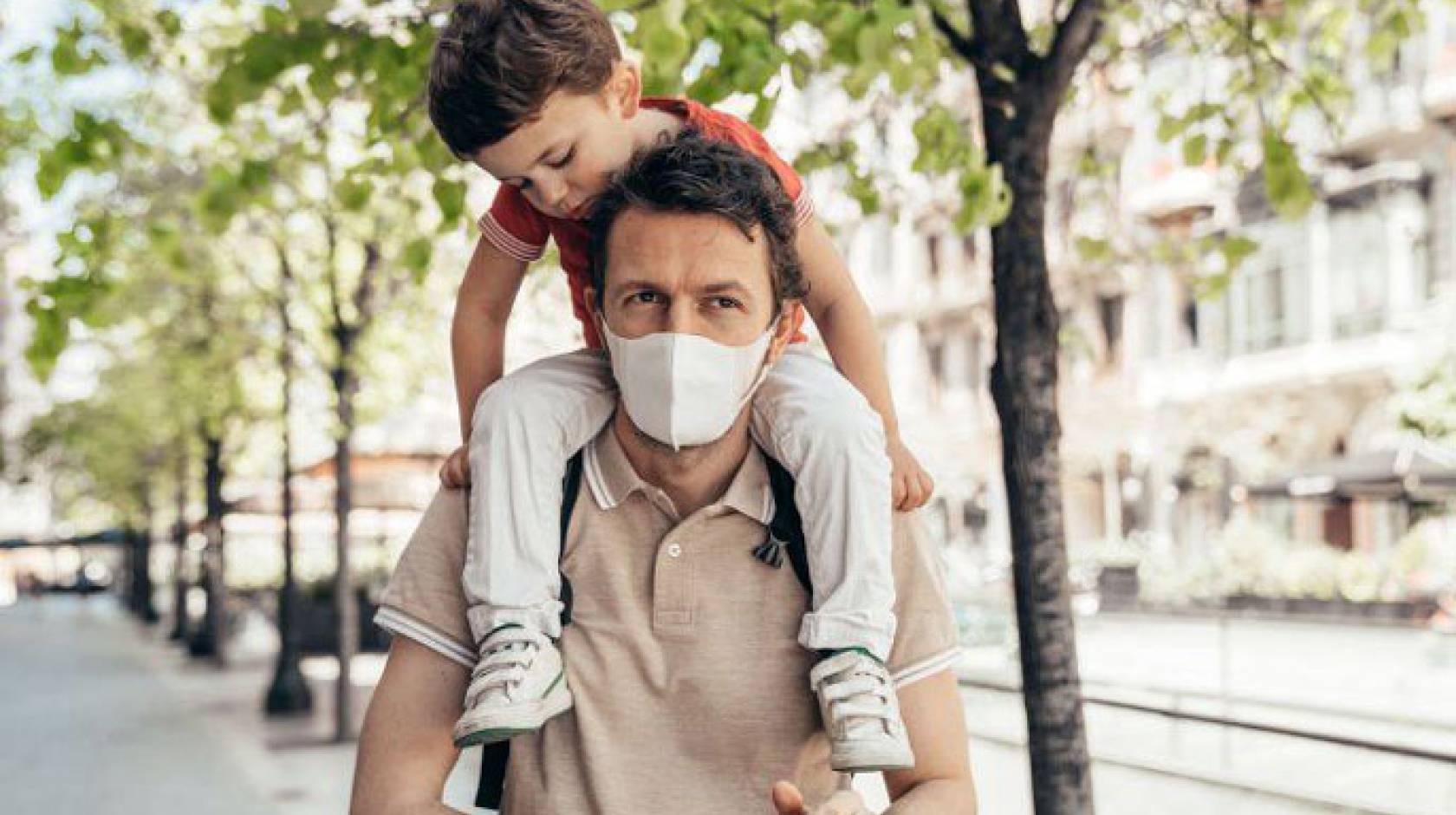 Father wearing a mask carrying a child