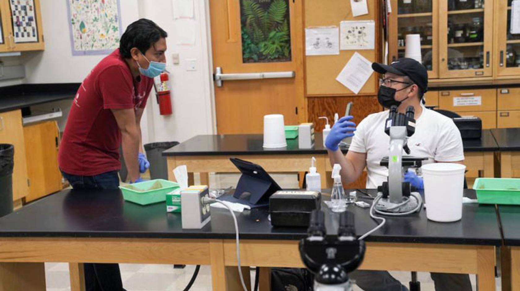 UC Davis students, masked, communicating in a lab