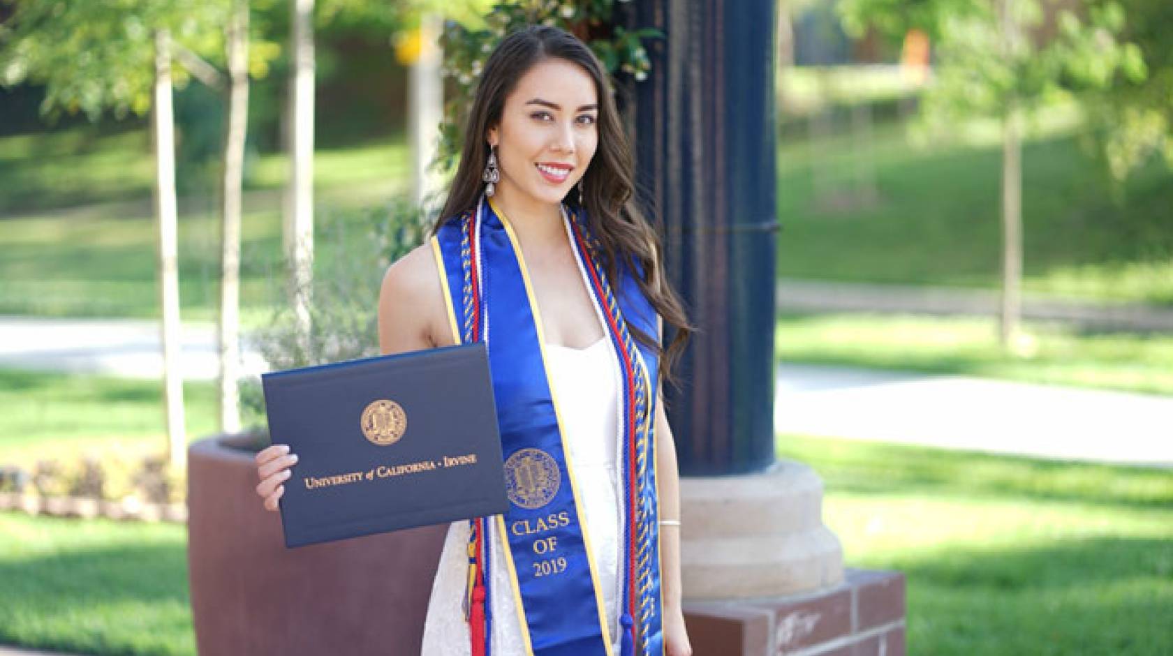 Monica Mary Xu English with her diploma, cap and gown