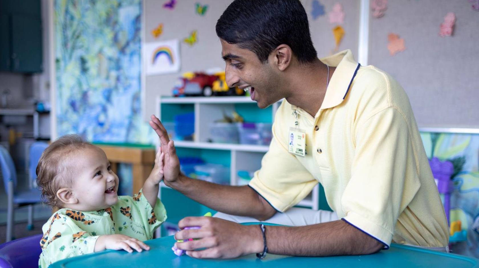 Neeraj Senthil high-fives a laughing baby at the children's hospital