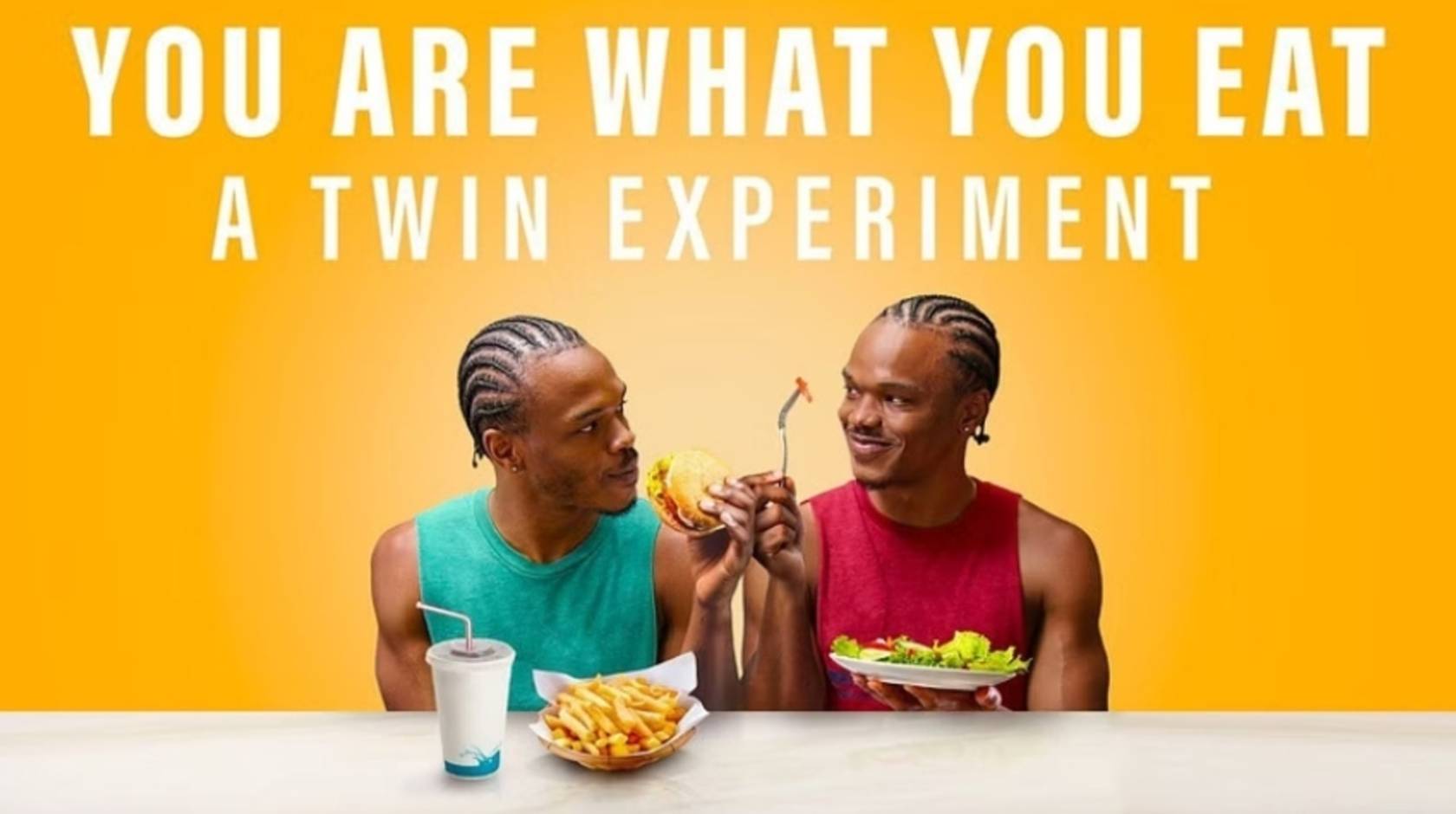 A photo of two young African American men, twins, one eating fast food and the other eating a salad