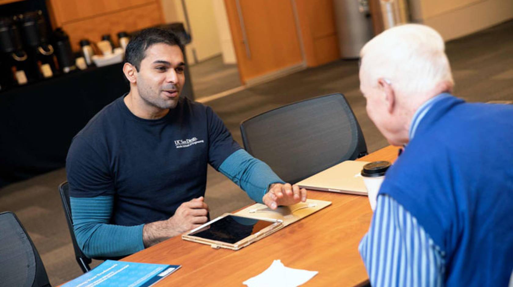 Gopesh Tilvawala speaks to someone across a table