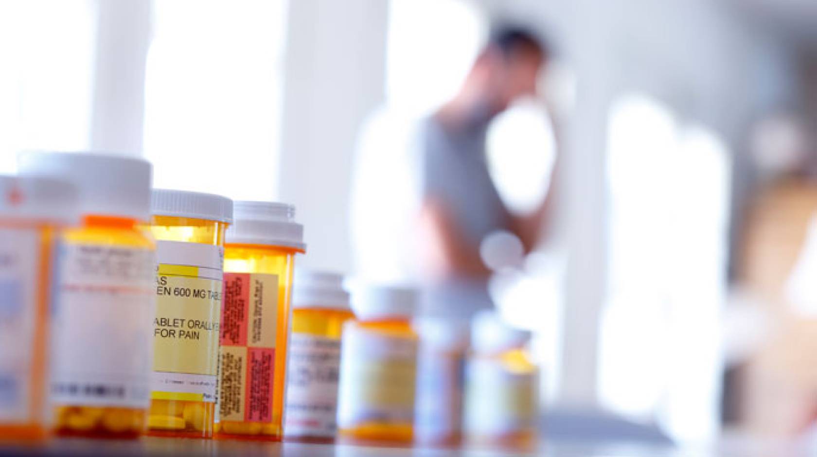 Opioid bottles with a man in the background