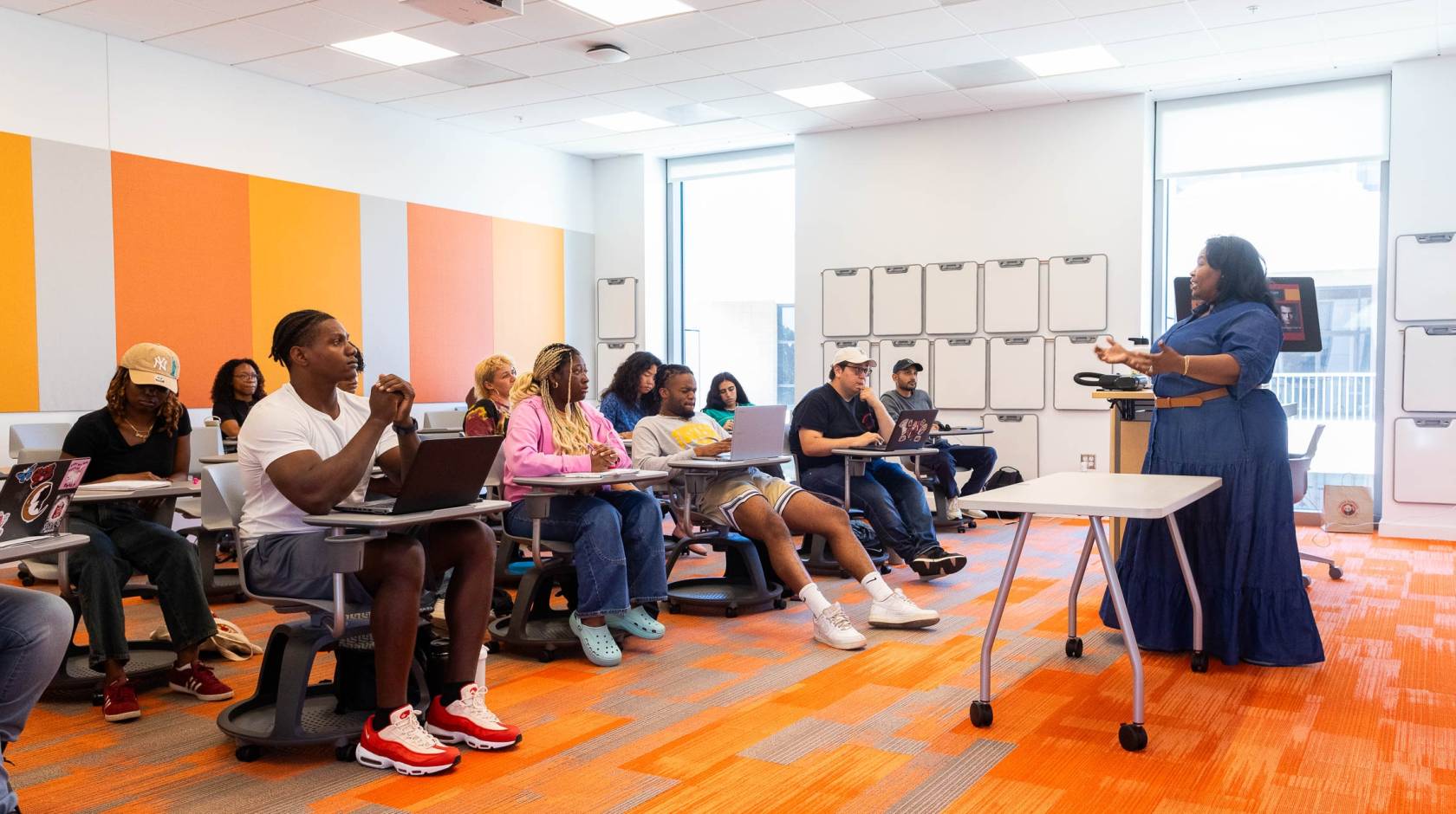 A teacher lectures before a class of students seated at desks