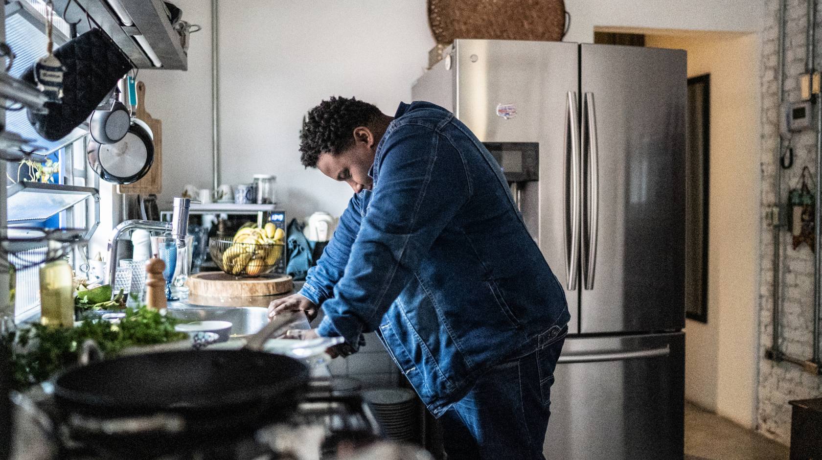 Man leans against counter in a kitchen, looking overwhelmed