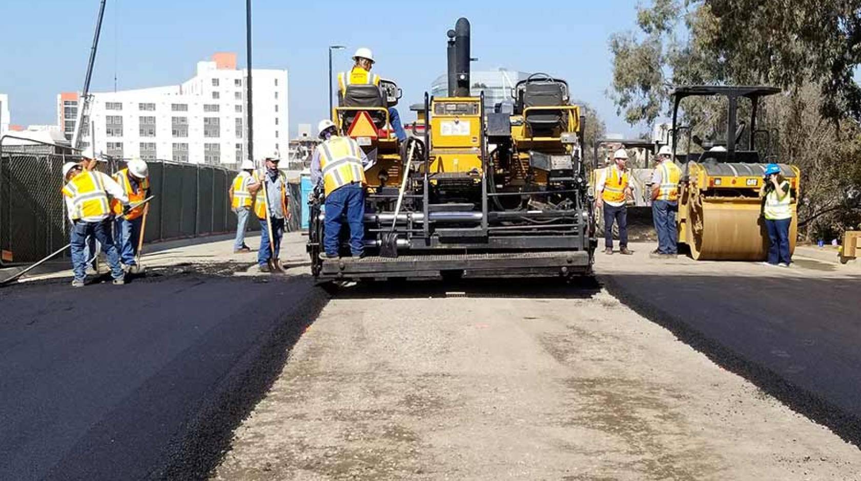 A work crew paves the road with material made of recycled plastic