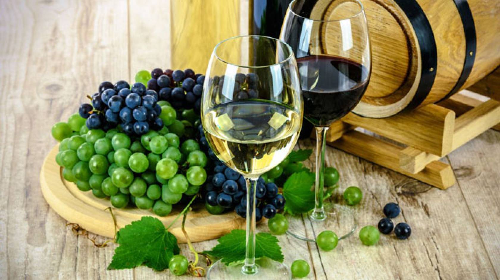 Red and white wine in glasses next to grapes