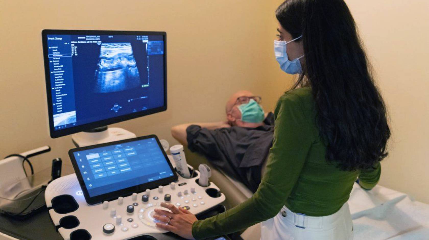 A doctor looking at a patient's ultrasound while the patient reclines nearby