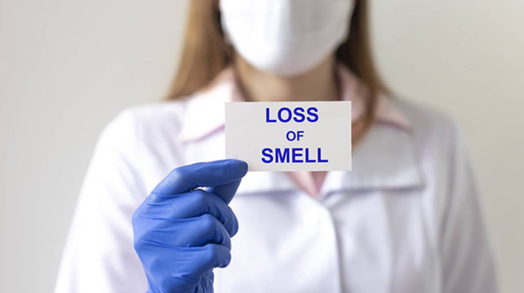 Nurse holds card saying 'loss of smell'