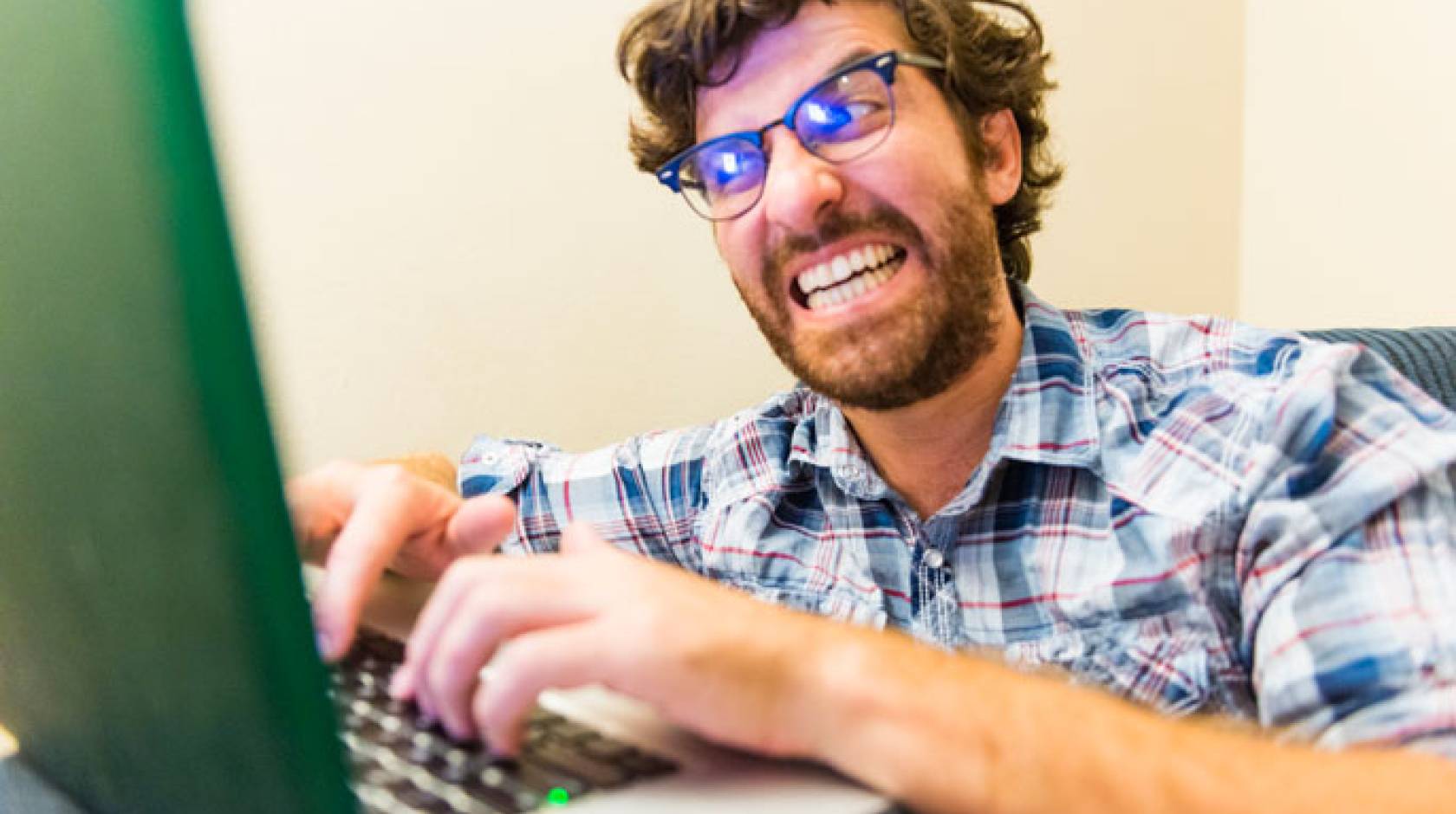 Outraged man typing on computer