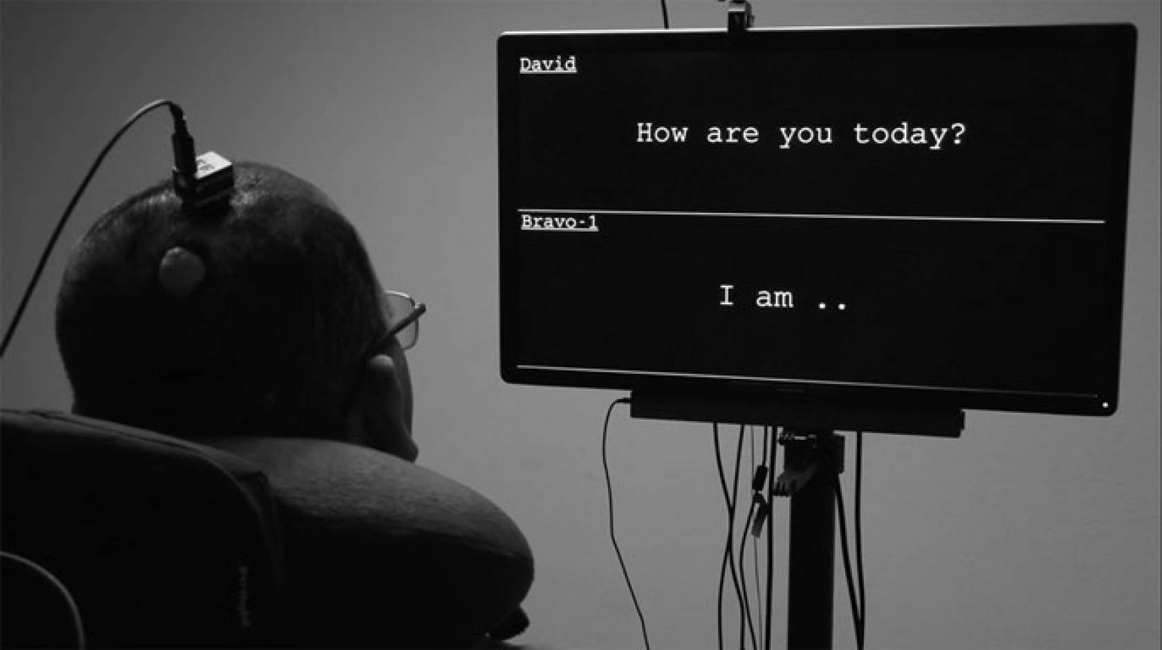 A man looks at a screen where his words appear while wearing a device on his head