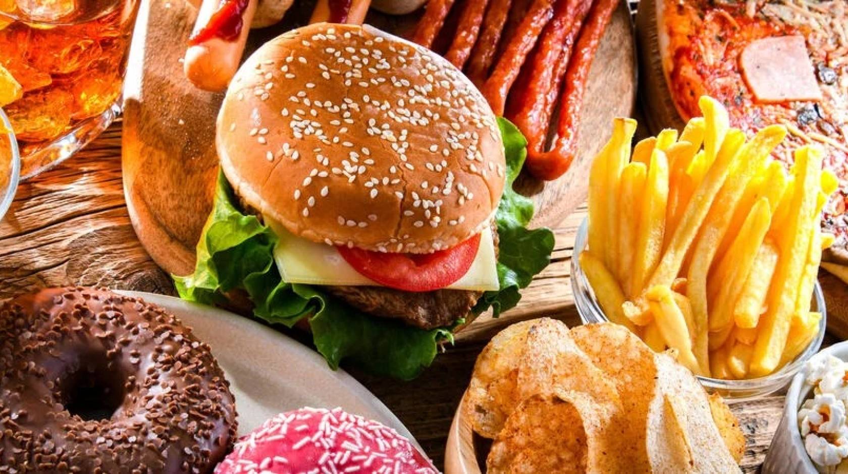 A photo of a table with chips, beer, a burger, pizza, french fries, tacos and ribs