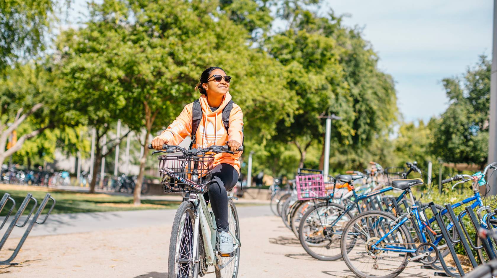 A student smiling in sunglasses riding a bike
