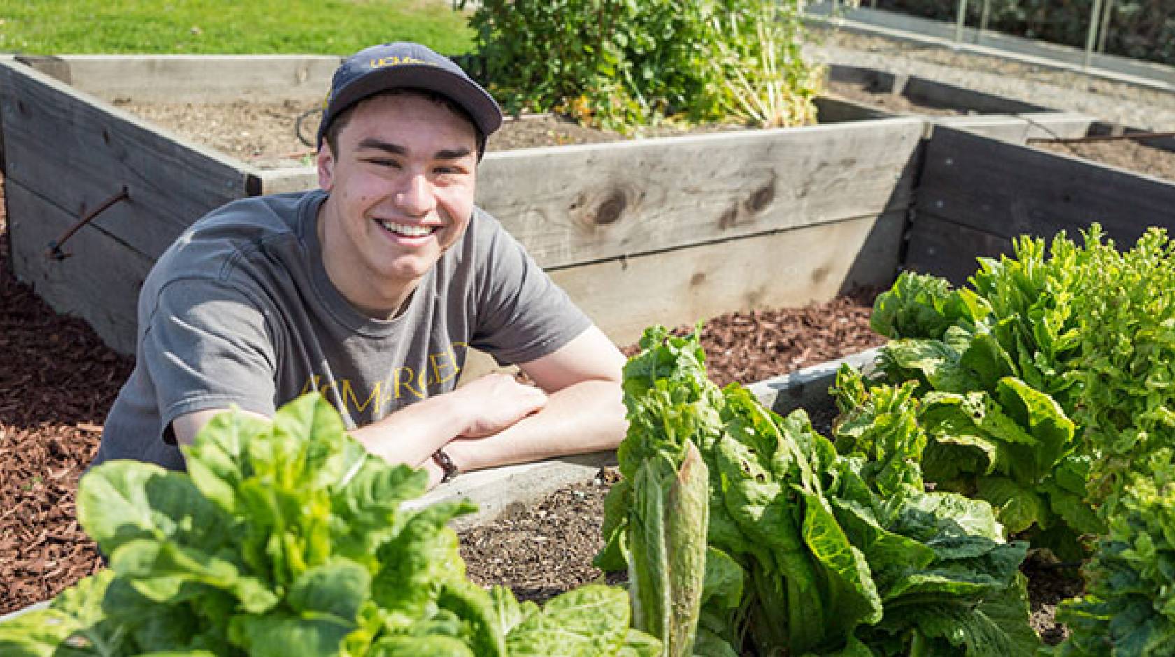 Young man smiles in campus garden