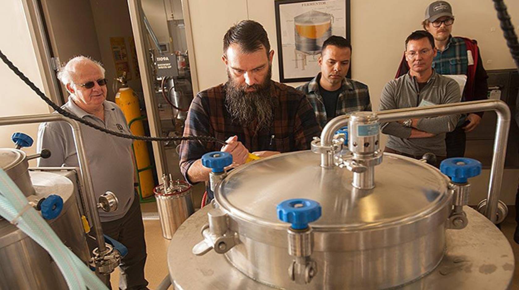 Professor Charlie Bamforth, left, and brewer Joe Williams, second from left, confer as beer is brewed in the UC Davis brewery.