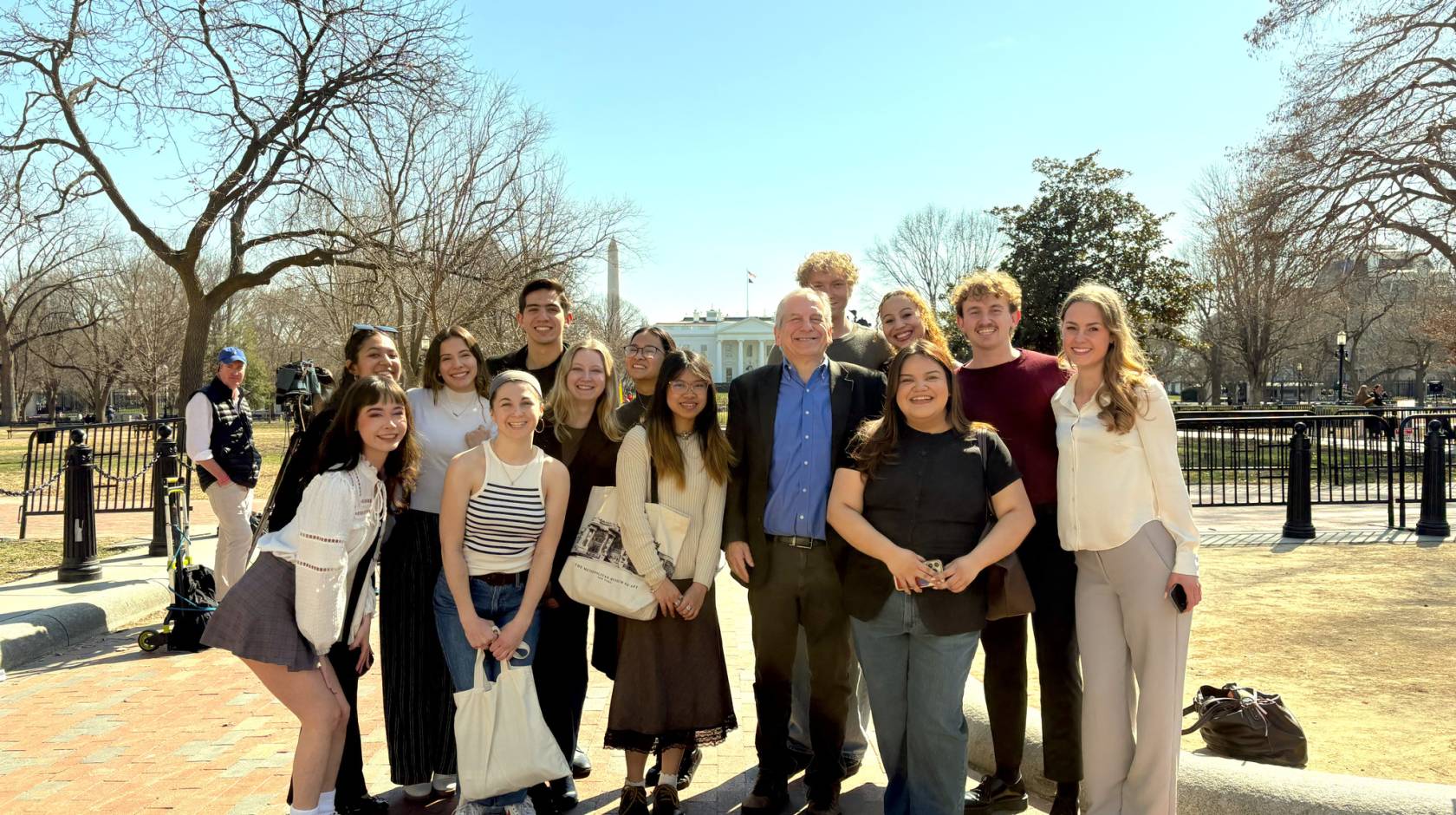 A group photo of people outside, Washington Monument and the White House behind