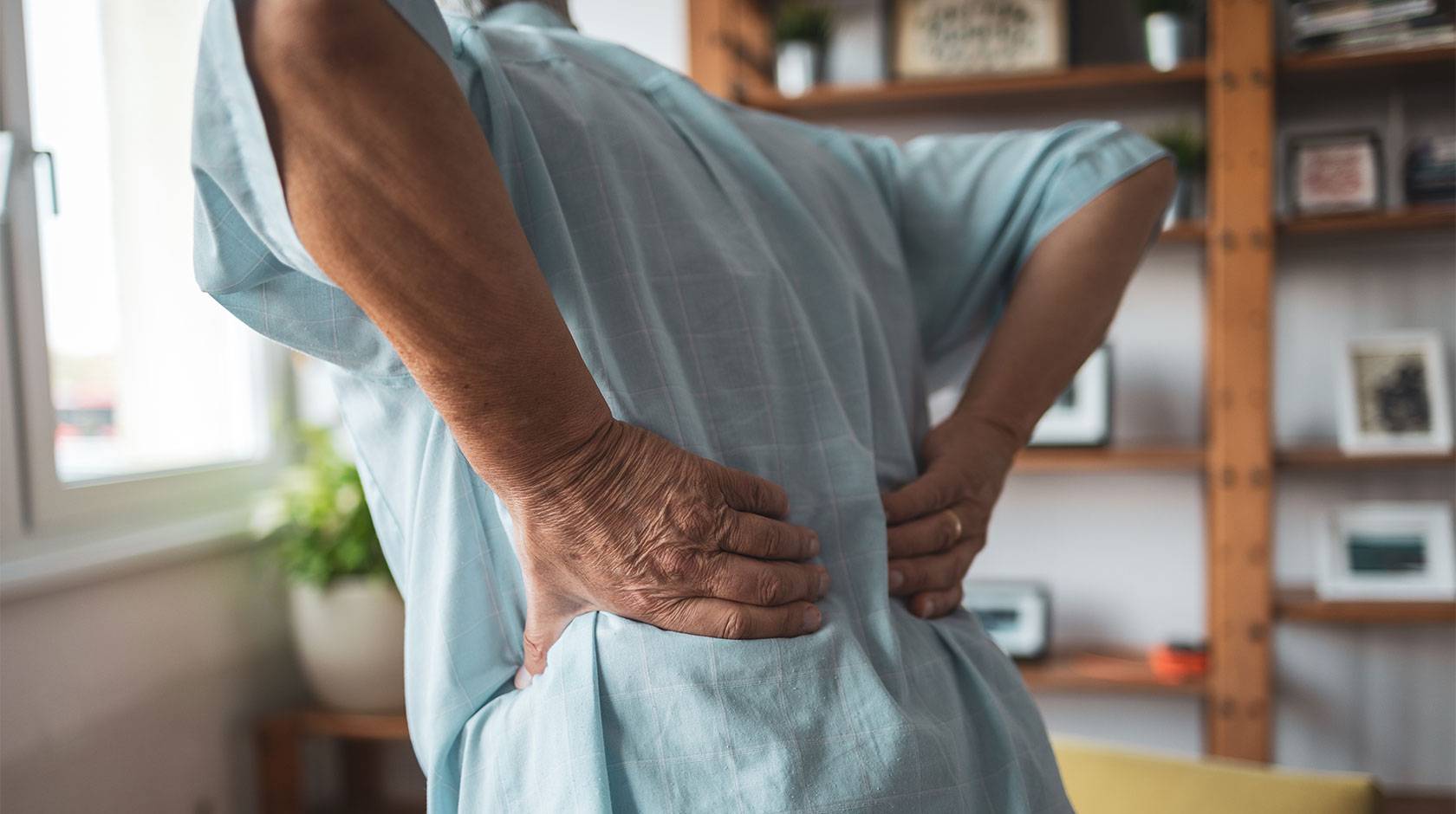 A person holds lower back as if to massage stiffness