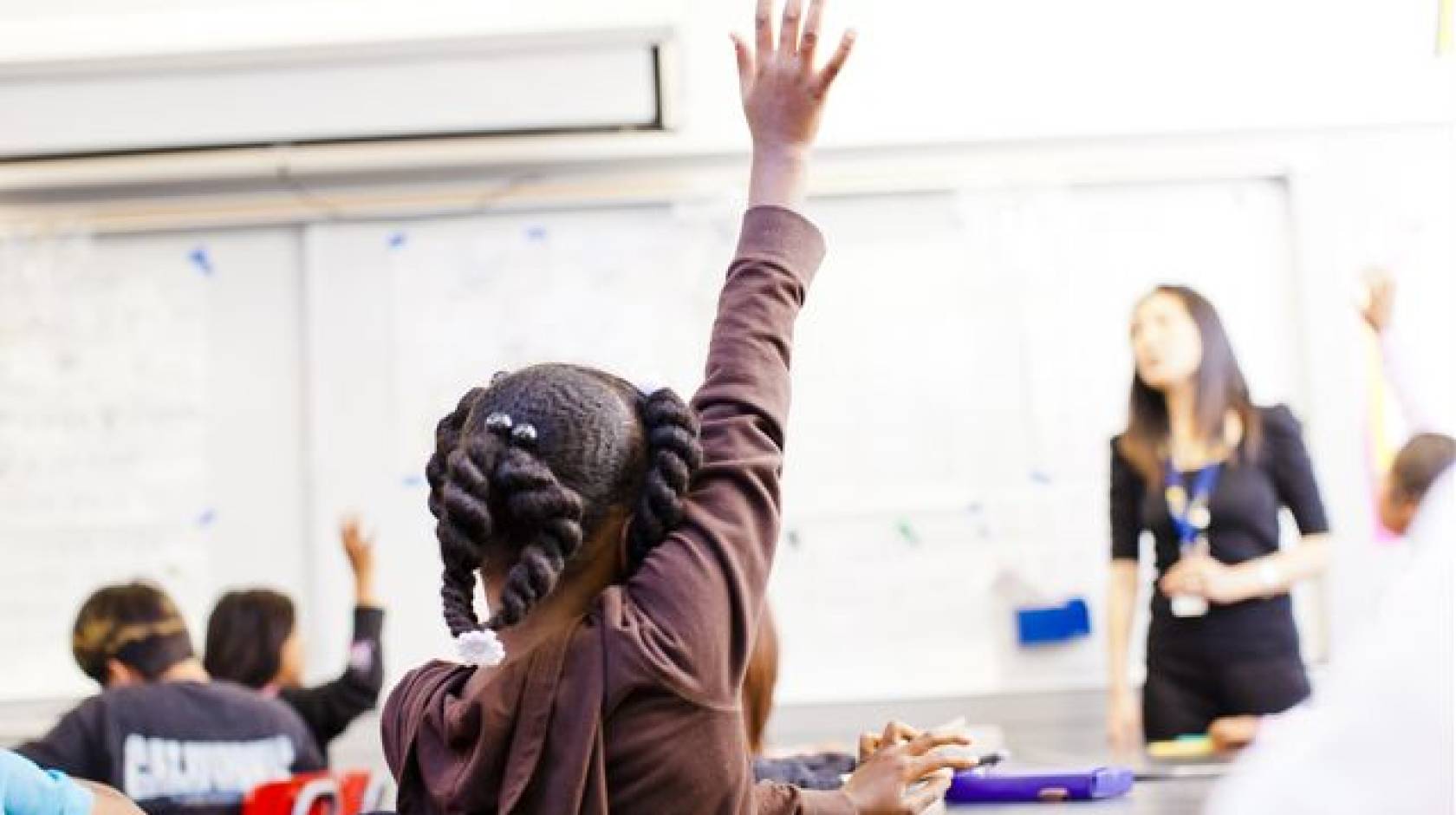 child raises hand in a classroom
