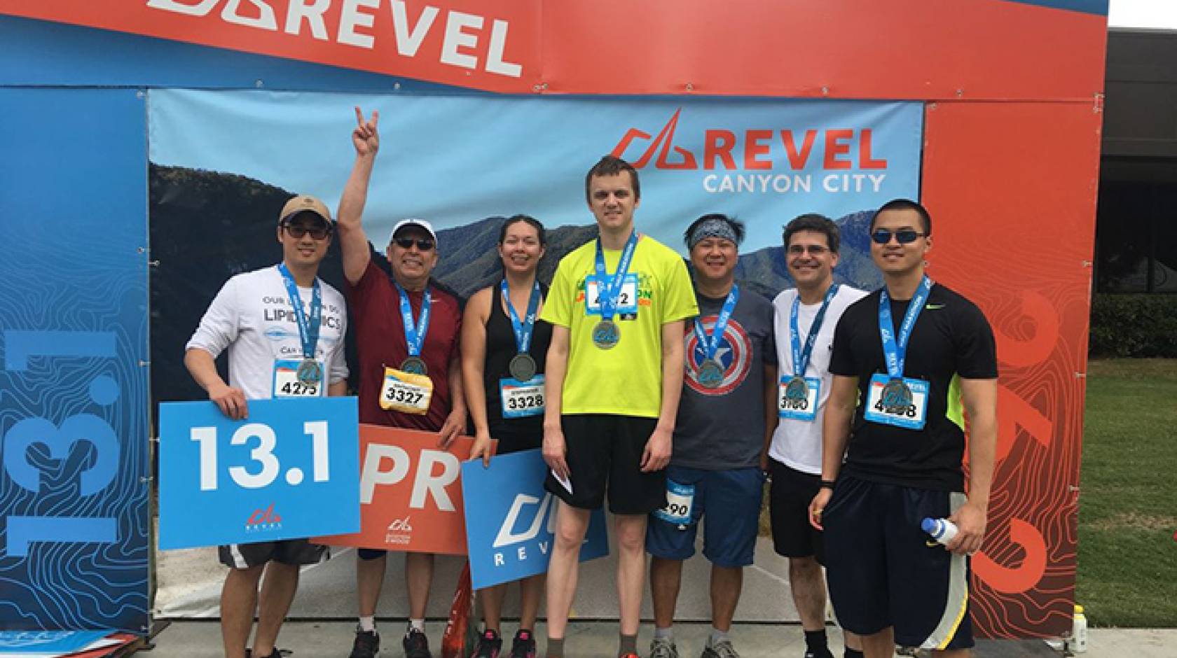 Tony Flores makes a victory sign as he stands at the finish of the half-marathon with his daughter, doctor and heart-failure researchers from UCLA, who ran to support Flores' efforts.