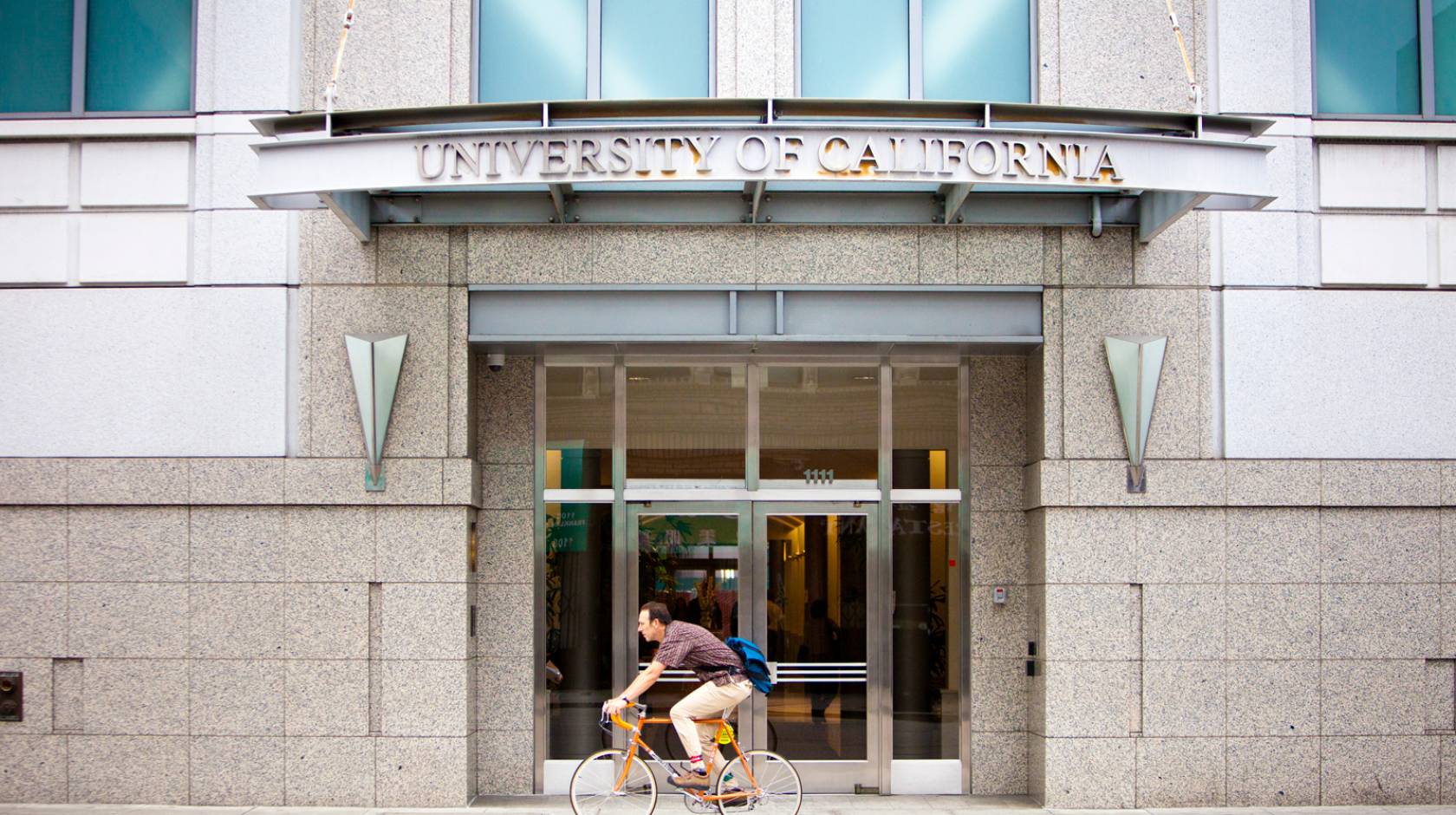 A cyclist goes by the UCOP building in Oakland, Calif.